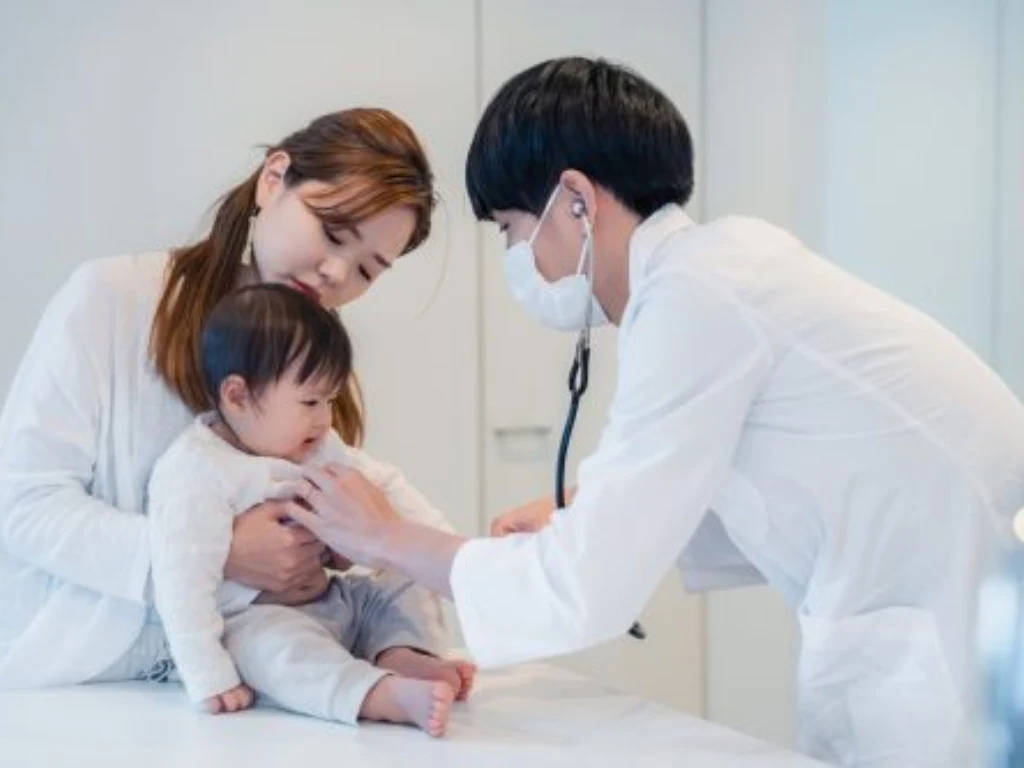 Doctor examining a young child with abdominal pain while the mother looks on