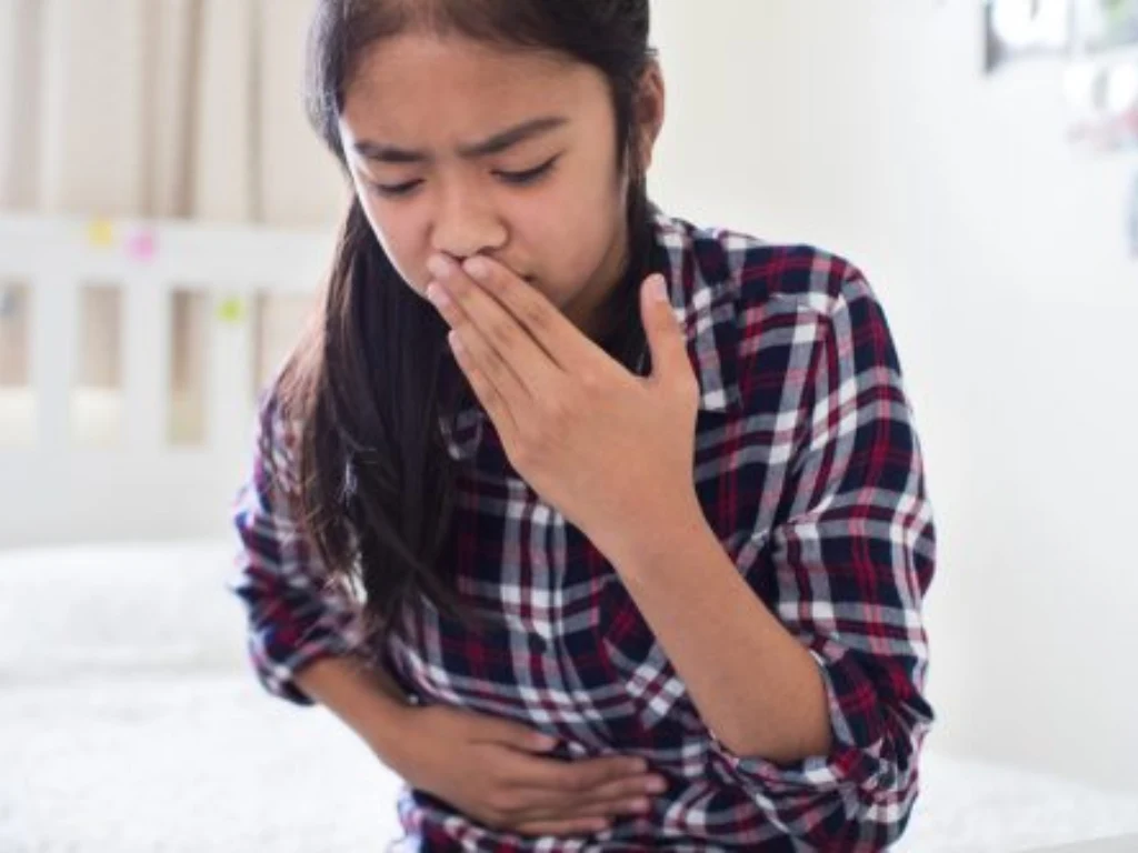 Child experiencing nausea and abdominal pain while covering their mouth
