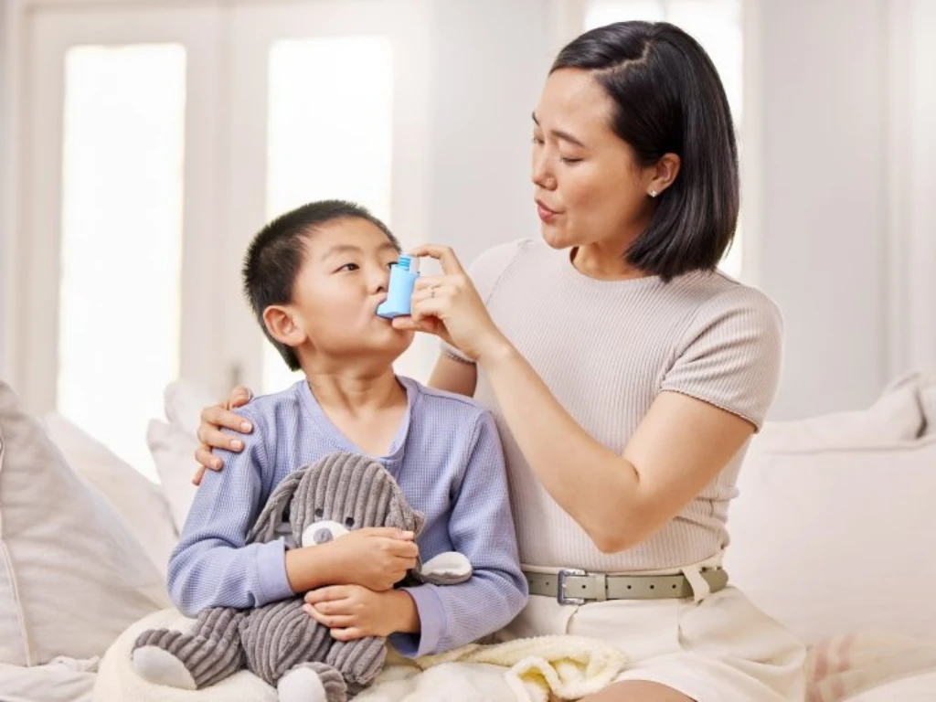 Orang tua membantu anak menggunakan inhaler untuk mengatasi serangan asma